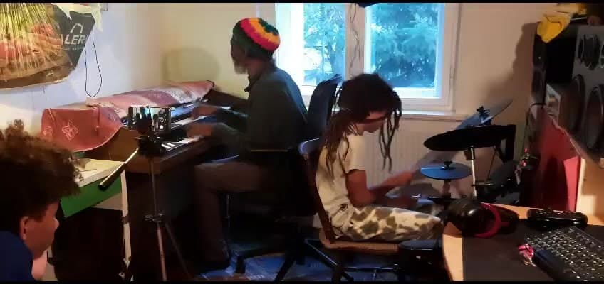 Studio: am Keyboard ein Musiker mit Strickmütze in Rot, Gold und Grün, daneben wird E-Schlagzeug gespielt